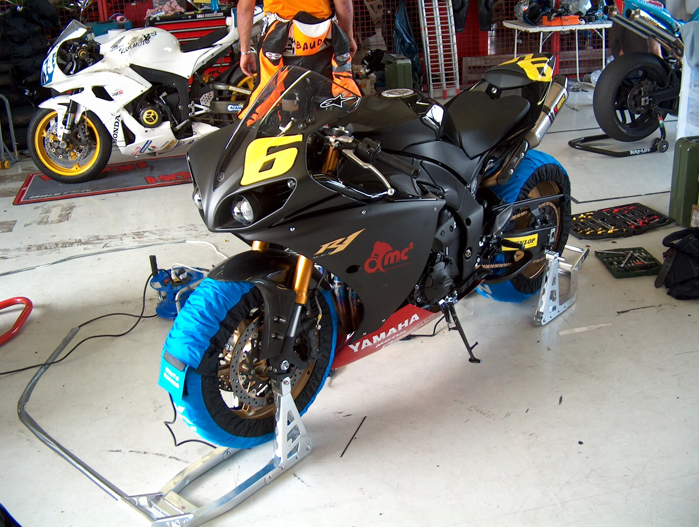 Race bikes on stands under tyre warmers in the garage